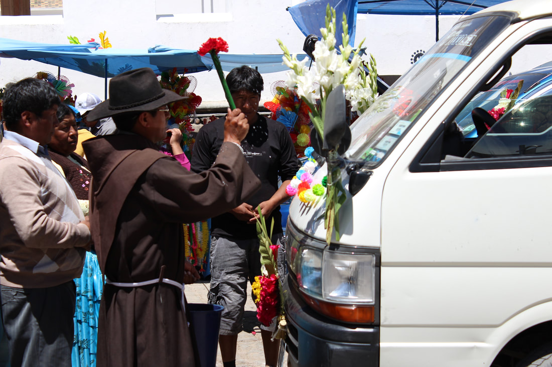 At the main plaza in Copacabana, Bolivia, a priest showers a car with holy water, part of the ancient Andean practice of the 