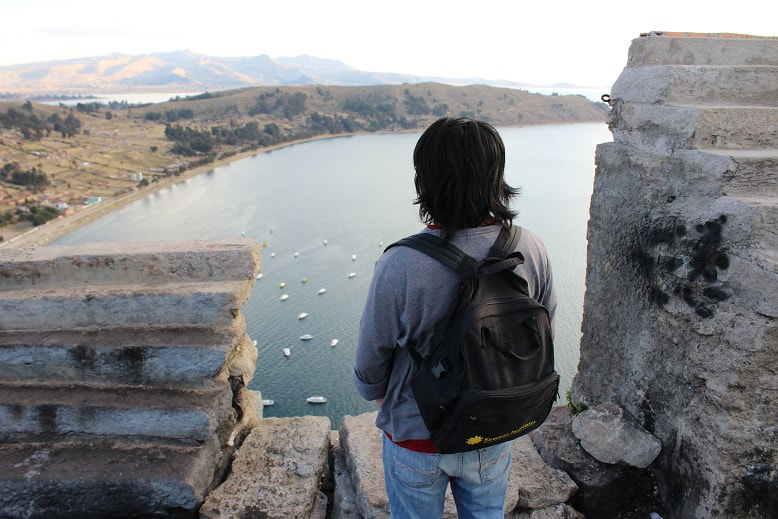 A traveler stares out over Lake Titicaca from his vantage point at El Calvario, a destination for tourists and devout Catholics alike