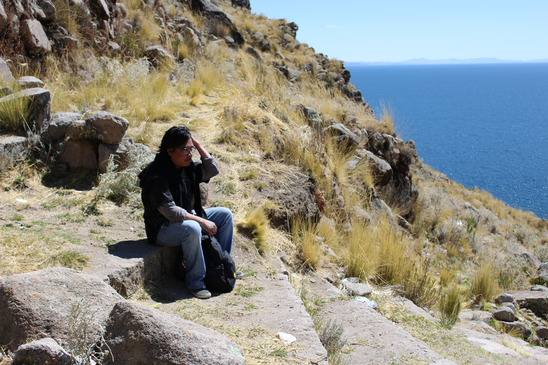 A hiker takes a break on a mountain overlooking Lake Titicaca
